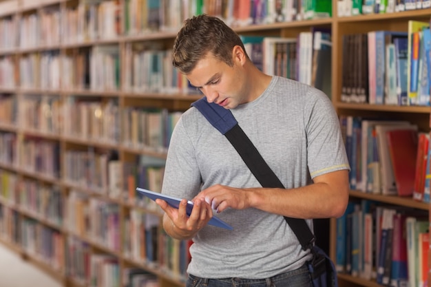 Beau étudiant sans sourire regardant la tablette