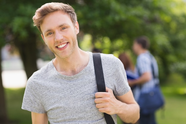 Beau étudiant souriant à la caméra à l&#39;extérieur sur le campus