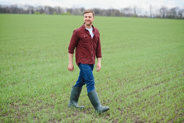 Beau fermier Jeune homme marchant dans un champ vert Agriculture de printemps