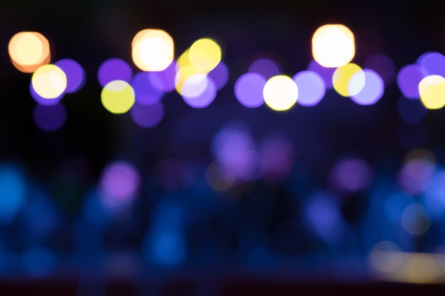 Beau fond flou de performances nocturnes avec des lumières jaunes, violettes et bleues.