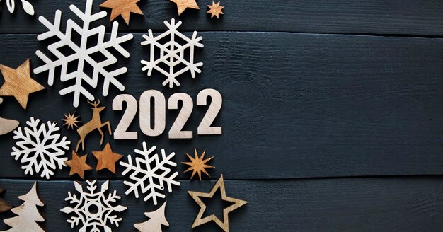 Le beau fond de noël avec beaucoup de petites décorations en bois et numéros en bois 2022 sur le bureau en bois foncé.