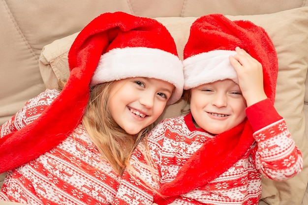 beau frère et soeur en pyjama de Noël et bonnets de noel au lit