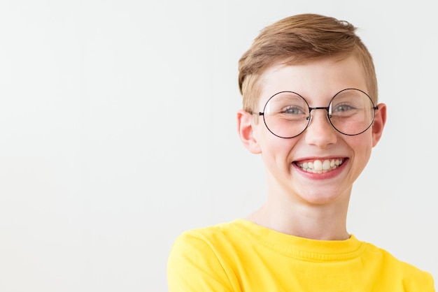 Beau garçon adolescent qui rit avec de grandes lunettes et un t-shirt jaune