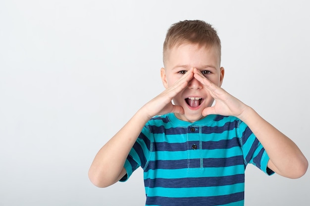 Beau garçon a l'air en colère L'enfant est offensé menace montre un poing Enfant agressif rancunier en colère Portrait sur fond de studio blanc Concept d'émotions humaines pour enfants