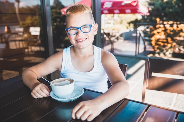 Beau garçon avec des lunettes dans un restaurant buvant du café