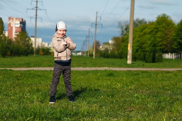 Beau garçon de six ans jouant, sautant, courant, souriant dans le parc.