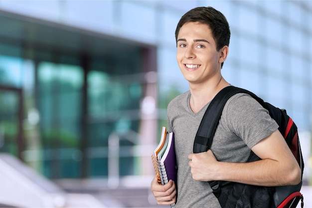 Beau garçon souriant avec des livres sur fond