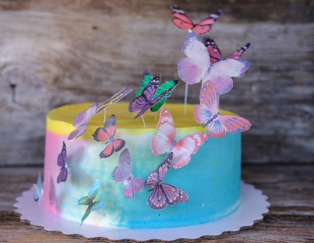 Beau gâteau de bébé fait maison avec de la crème multicolore et des papillons