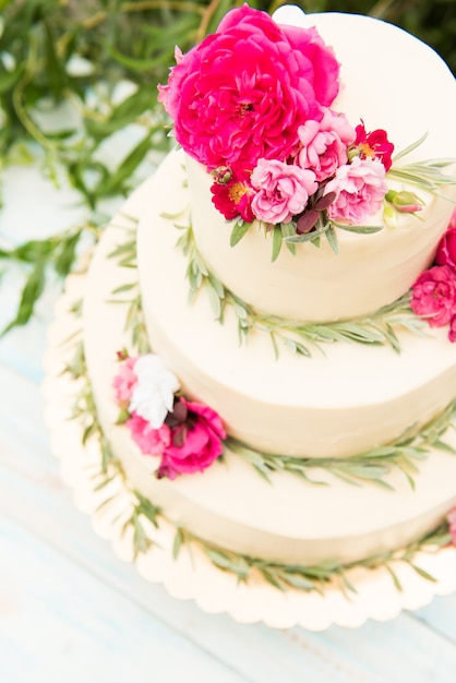 Beau gâteau de mariage avec des fleurs, à l'extérieur. Trois niveaux