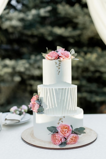 beau gâteau de mariage près de l'arc de mariage le soir