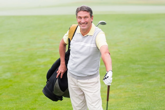 Beau golfeur debout avec un sac de golf