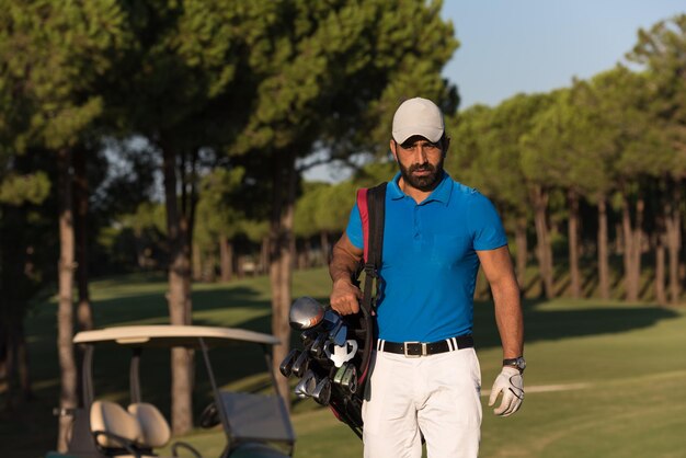 beau golfeur du moyen-orient portant un sac et marchant jusqu'au prochain trou du terrain de golf