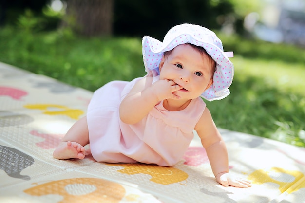 Beau gosse souriant jouant dans le jardin. Heureux bébé mignon s&#39;amuser dans le parc. Doux bébé ensoleillé dans le panama