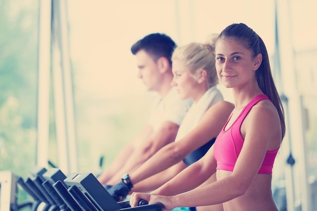 Beau groupe d'amis de jeunes femmes s'exerçant sur un tapis roulant à la salle de gym moderne et lumineuse