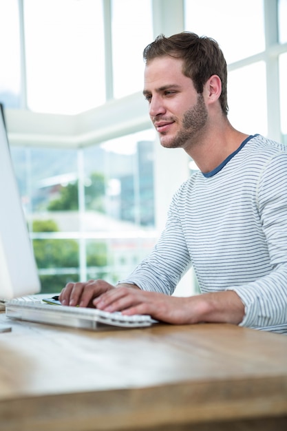 Beau hipster travaillant sur ordinateur dans un bureau lumineux