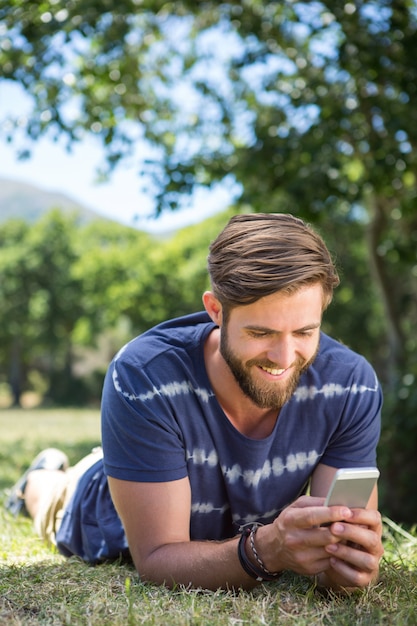 Beau hipster en utilisant le téléphone dans le parc