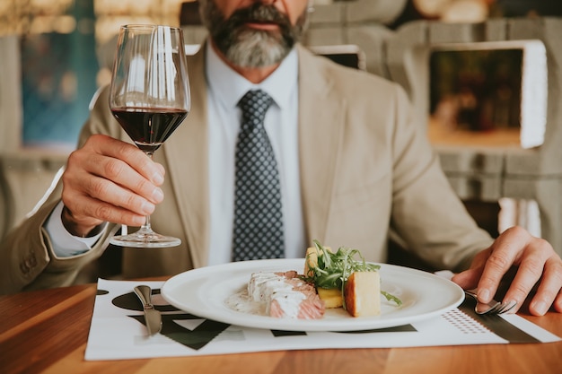 Beau homme d&#39;affaires d&#39;âge moyen en train de déjeuner et de boire du vin rouge au restaurant