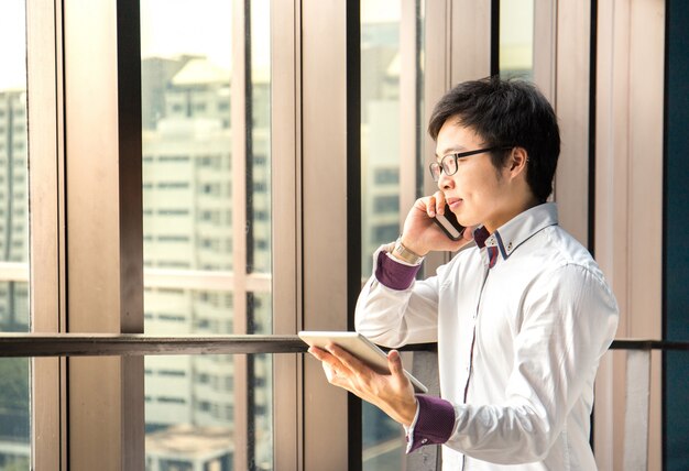 Beau homme d&#39;affaires travaillant avec tablette et téléphone intelligent au bureau