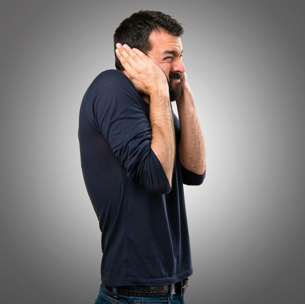 Beau homme à la barbe couvrant ses oreilles sur fond gris