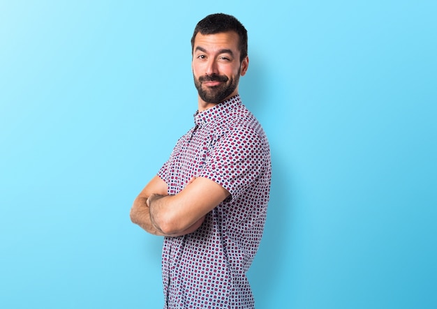 Beau homme avec les bras croisés sur fond coloré