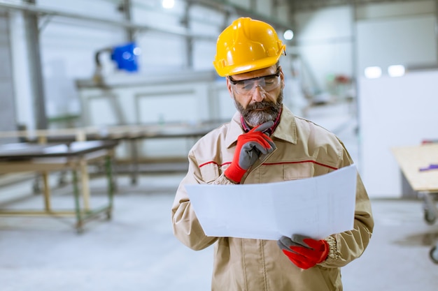 Beau ingénieur mature regardant plan dans l&#39;usine