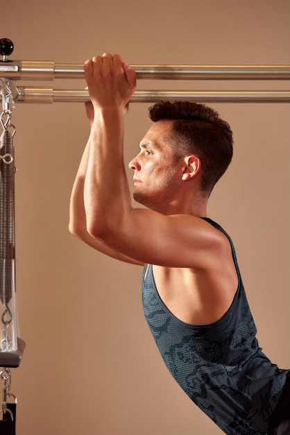 Beau instructeur masculin de pilates effectuant des exercices de remise en forme d'équilibre d'étirement sur un petit équipement de baril au studio de pilates intérieur intérieur moderne