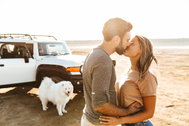 Beau jeune couple amoureux embrassant tout en se tenant à la plage, voyage de vacances