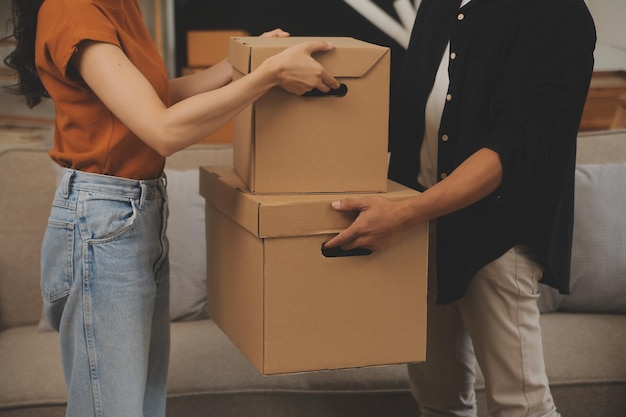 Beau jeune couple amoureux s'amusant à déballer des objets de boîtes en carton tout en emménageant ensemble dans leur nouvel appartement
