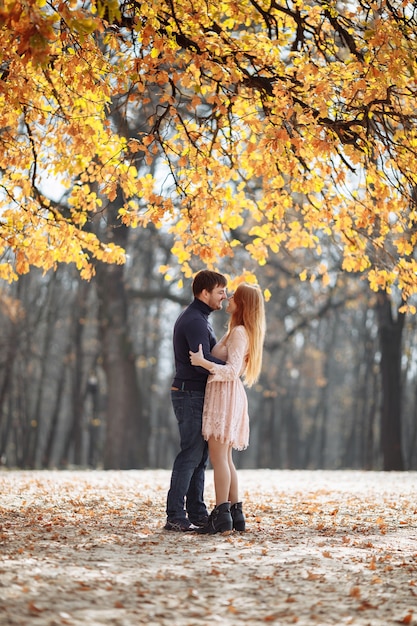 Beau jeune couple amoureux souriant joyeusement sur le fond des feuilles jaunes sur les arbres