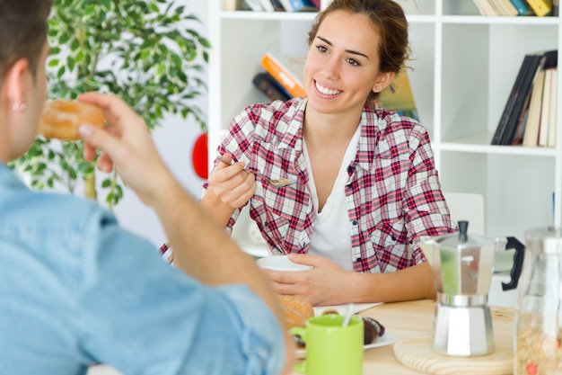 Beau jeune couple appréciant le petit déjeuner dans leur nouvelle maison.