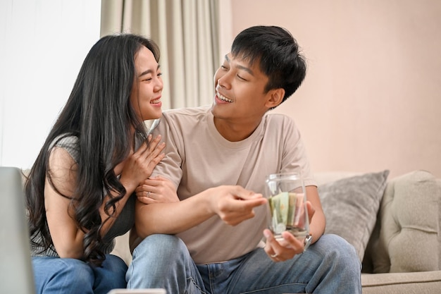 Un beau jeune couple asiatique nouvellement marié planifie leurs économies ensemble dans le salon.
