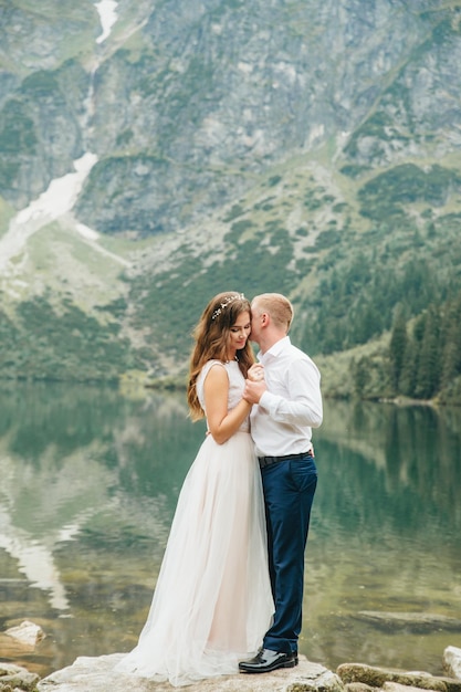 Un beau jeune couple au bord du lac dans les montagnes de Tatra en Pologne Morskie Oko