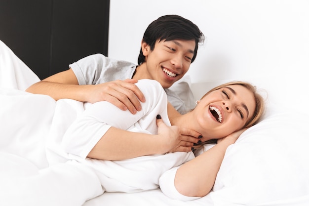 Beau jeune couple, couché dans son lit, riant