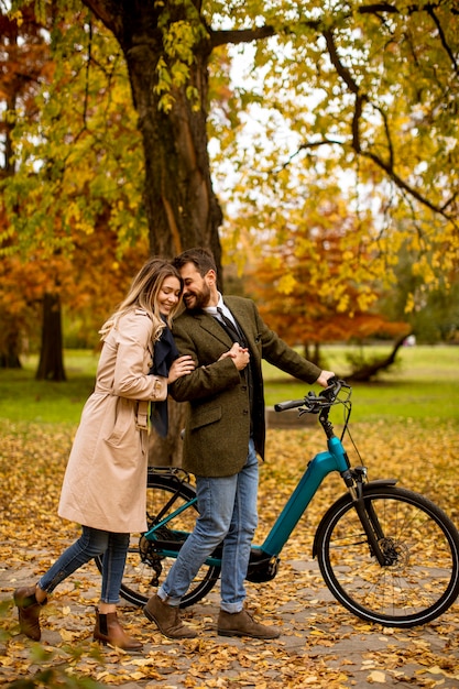 Beau jeune couple dans le parc en automne avec vélo électrique