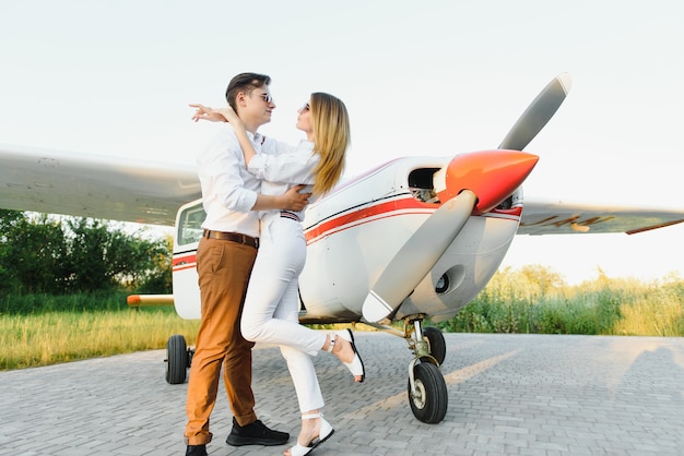 Beau jeune couple élégant en tenue officielle debout dans un avion privé