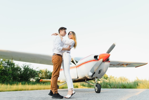 Beau jeune couple élégant en tenue officielle debout dans un avion privé