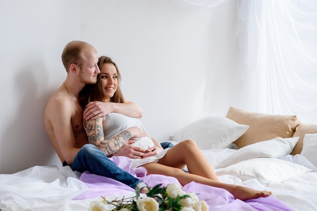 Beau jeune couple enceinte au lit