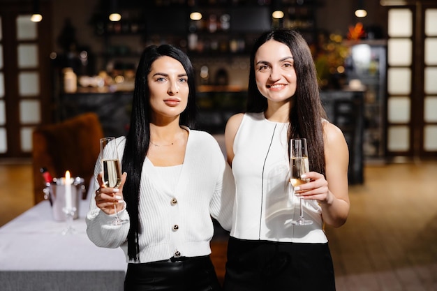 Beau jeune couple de femmes avec des verres de champagne célèbrent dans un restaurant de luxe