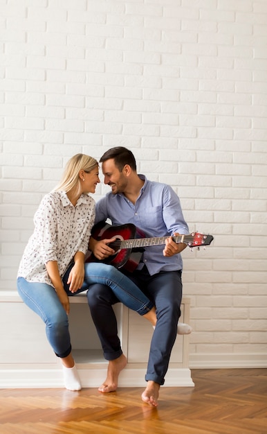 Beau jeune couple avec guitare dans la chambre