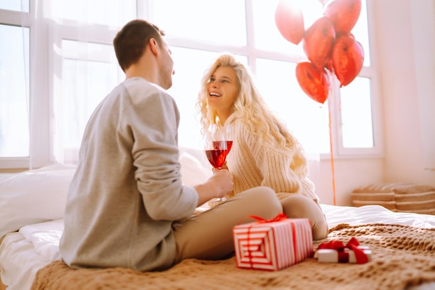 Beau jeune couple à la maison célébrant la Saint-Valentin Les amoureux se donnent des cadeaux