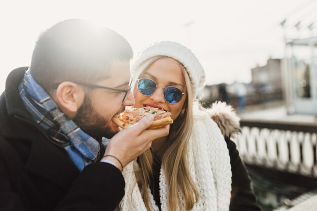 Beau jeune couple mangeant une pizza ensemble.