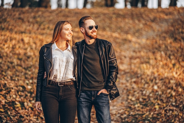 Beau jeune couple marchant dans le parc en automne par une journée ensoleillée