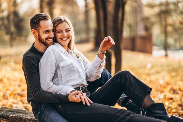 Photo beau jeune couple marchant dans le parc d'automne par une journée ensoleillée
