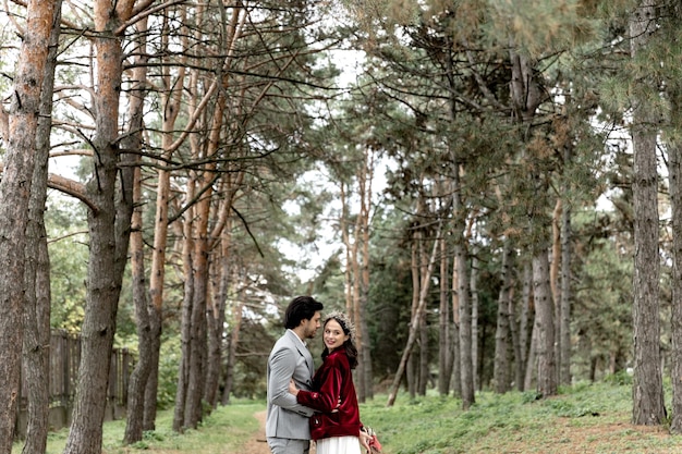 Beau jeune couple de mariage étreignant et marchant dans une forêt de pins photo de haute qualité