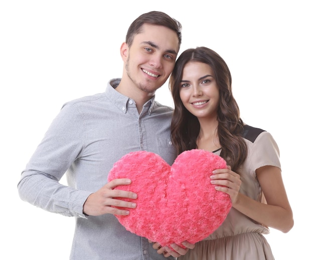 Beau jeune couple avec oreiller en forme de coeur sur fond blanc