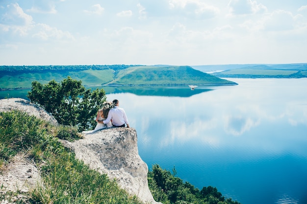 beau jeune couple posant sur le rocher près du lac