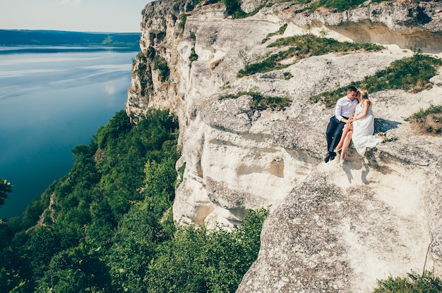 beau jeune couple posant sur le rocher près du lac