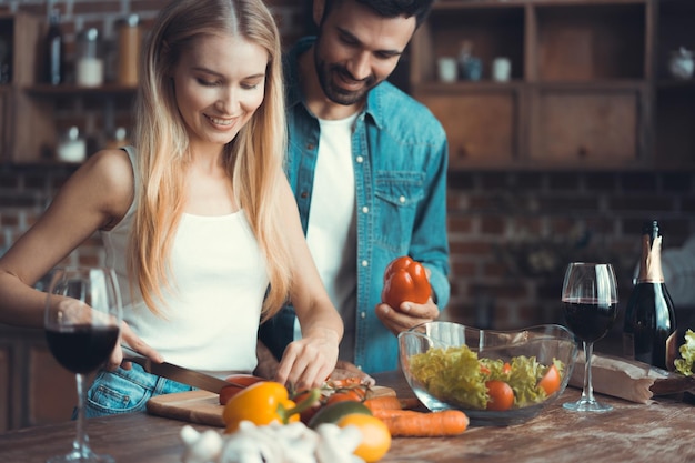 Beau jeune couple préparant un repas sain ensemble tout en passant du temps libre à la maison