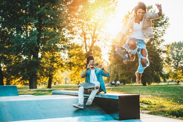 Photo beau jeune couple profitant de l'extérieur et prenant des photos dans le parc de skate de la ville.