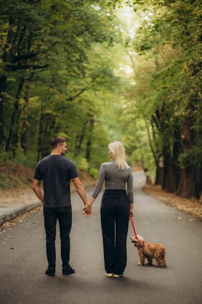 Beau jeune couple en promenade dans la forêt d'automne avec un chien